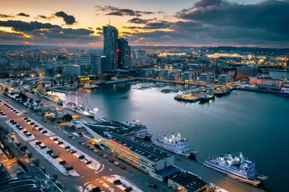 Soleco - Widok z lotu ptaka na warszawski port o zachodzie słońca z widocznymi rurami GRP zintegrowanymi z infrastrukturą miejską w pobliżu doków i nowoczesnych budynków.