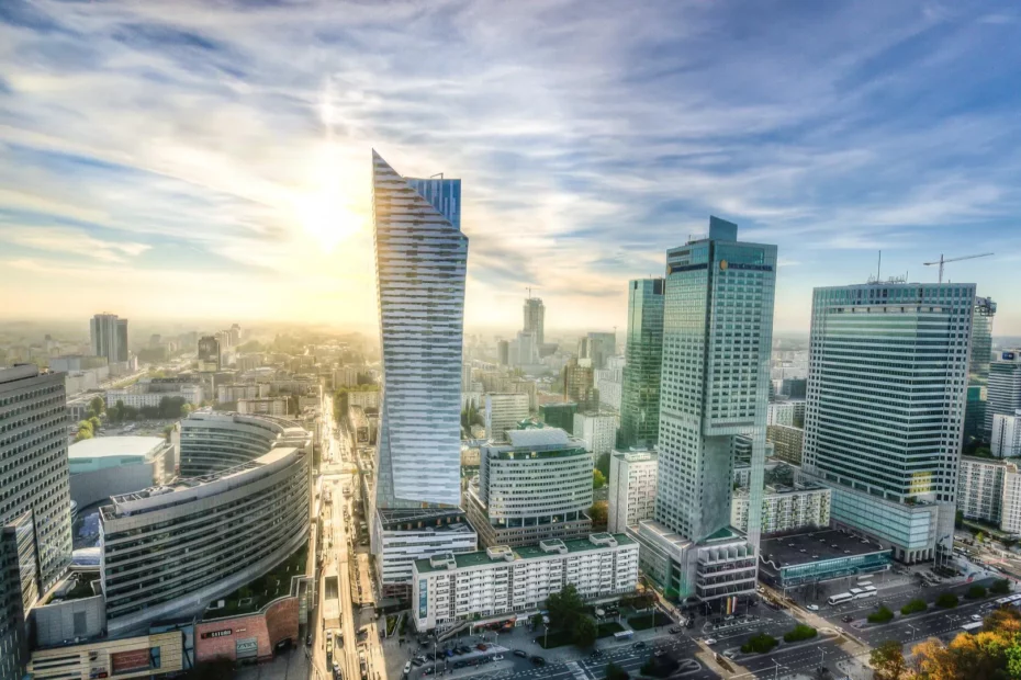 Soleco - Pejzaż Warszawy o zachodzie słońca z widocznymi rurami GRP w infrastrukturze miejskiej, prezentujący technologię bezwykopowej instalacji.